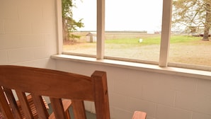 A wooden chair in a room with a window overlooking a grassy field and a small building. - 3bd, 1ba across from Pocosin Lakes Wildlife Refuge (Pantego)