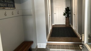 A hallway with a bench, a sign reading 'Marina Boat Club,' a door, and a potted plant.