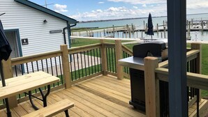 A wooden deck with a grill, a picnic table, and a building labeled 'RESTROOMS' in the background.