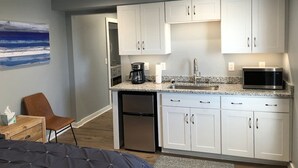 A compact kitchen with white cabinets, a built-in microwave, and a coffee maker.