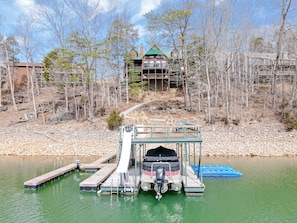 A dock with a motorboat, a wooden pier, and a building in the background.