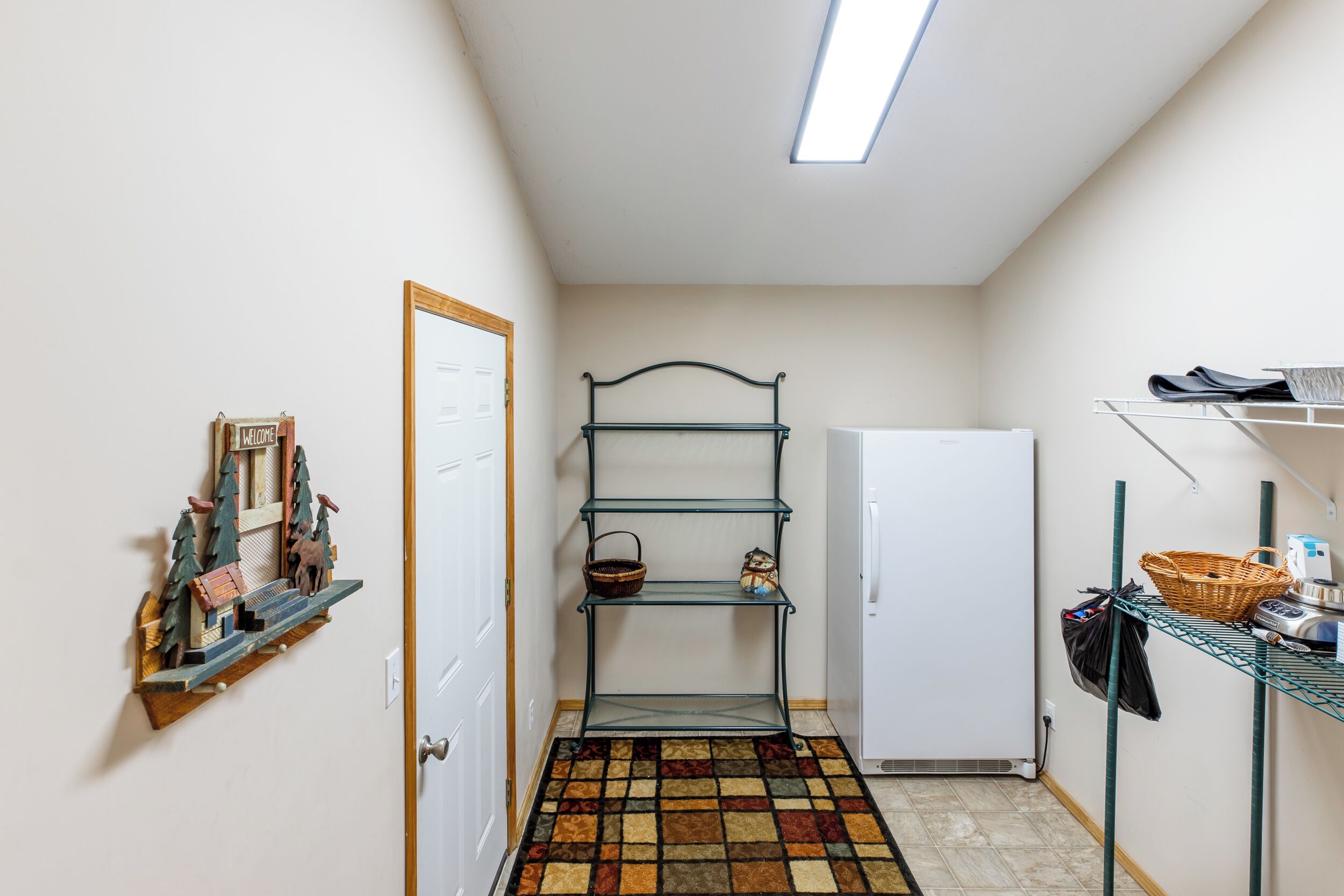 Un espace buanderie comprenant un étendoir en métal, un réfrigérateur et un tapis à motifs.