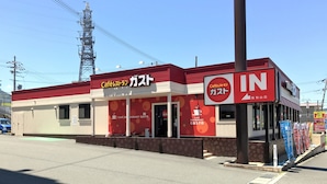A building with a red and white facade, a sign indicating a café restaurant, and a visible entrance. - Niko Niko Capsule Hotel (Fukuchiyama)