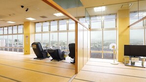 Una habitación amplia con ventanas grandes, un ventilador de techo y una silla de oficina negra.