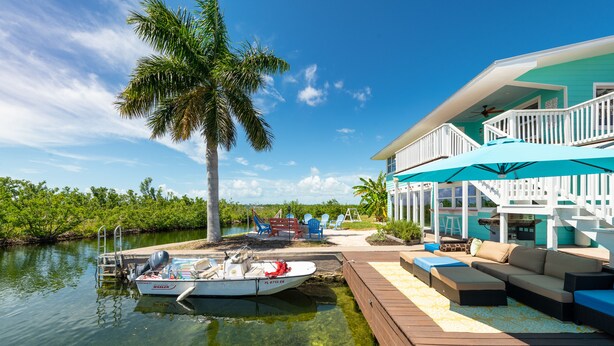 A waterfront property with a dock, boat, outdoor seating, and a covered area with stairs. - Private Paradise, Waterfront Home - 15 minutes from Key West (Key West)