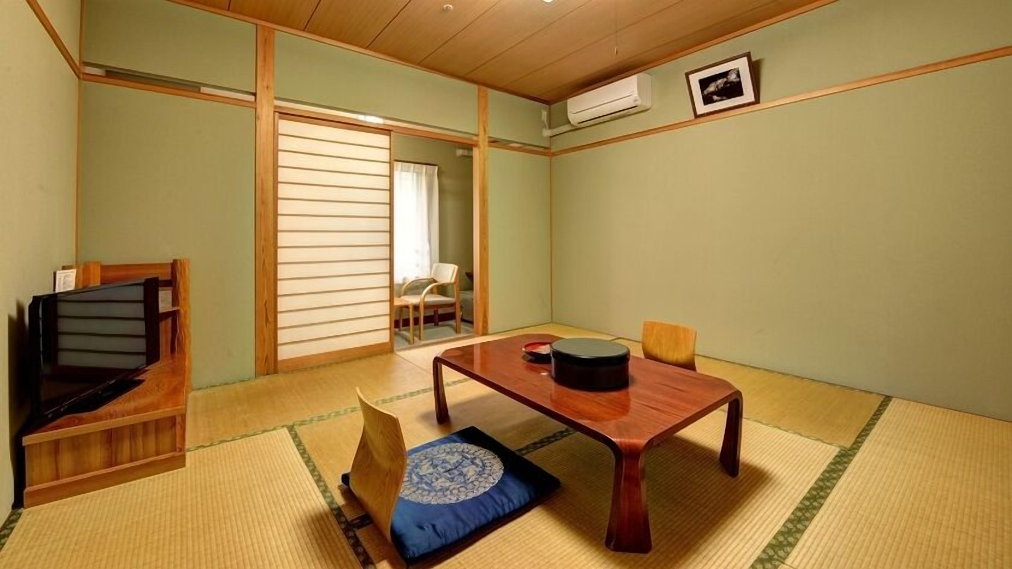 Una habitación japonesa tradicional con suelo de tatami, una mesa baja de madera, un sofá y una puerta corredera.