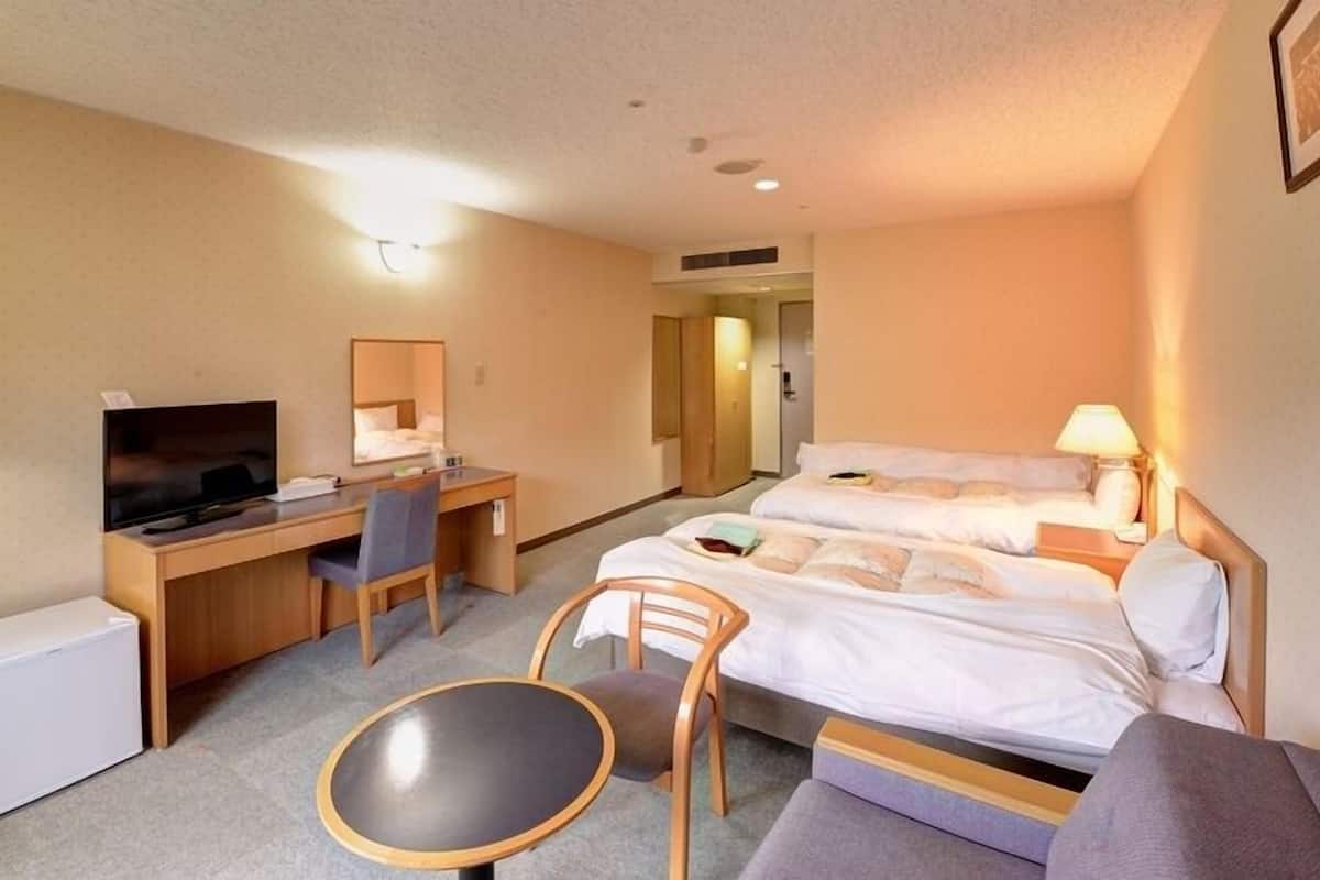 Une chambre d’hôtel équipée d’un lit, d’un bureau, d’une chaise, d’une télévision et d’une petite table.