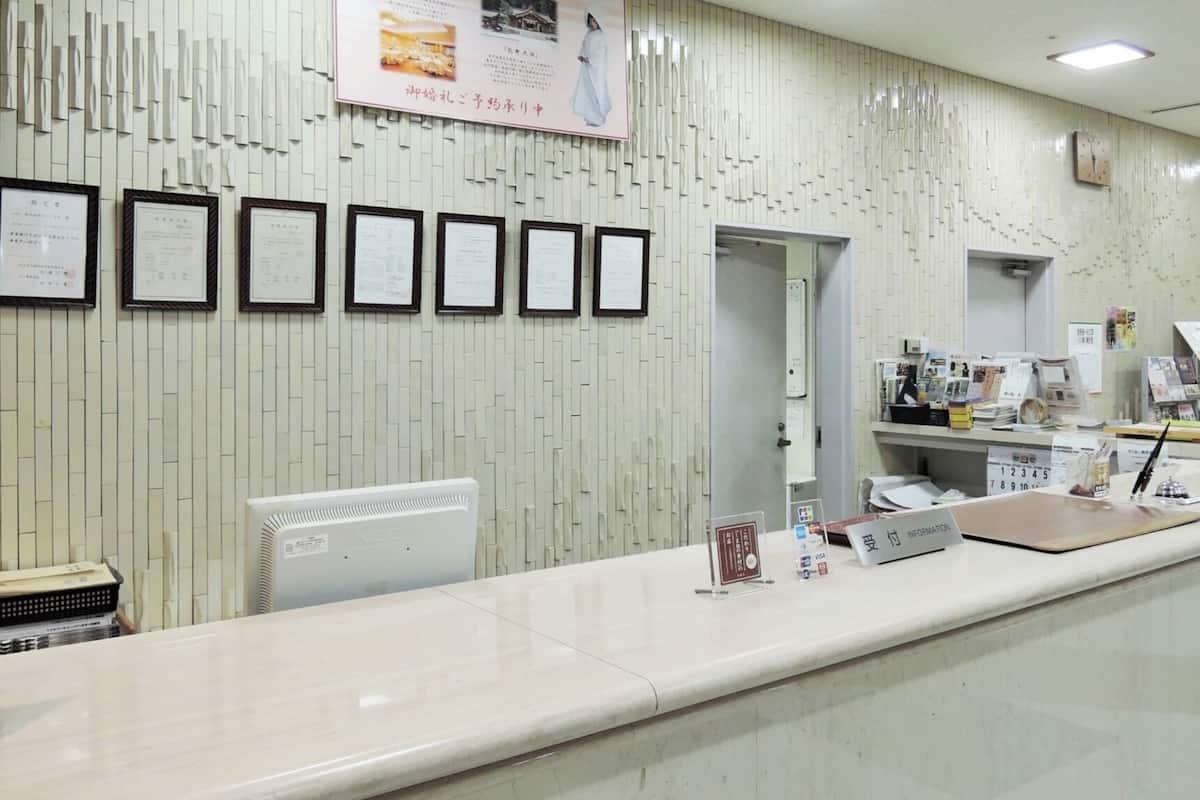 Un comptoir d’accueil avec des certificats encadrés, un ordinateur et des panneaux d’information.