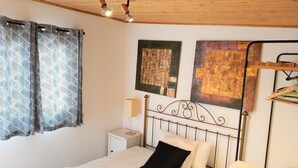A bedroom with a bed, a nightstand, a lamp, and two wall-mounted artworks.