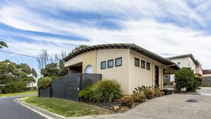 Une maison moderne de plain-pied, dotée d’un toit incurvé, d’un petit porche et d’une clôture noire.