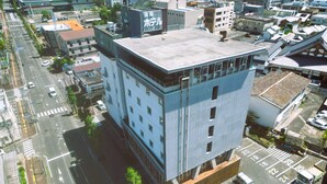 A multi-story building with a flat roof, large windows, and a parking lot with marked spaces. - Nobeoka Hotel (Nobeoka)