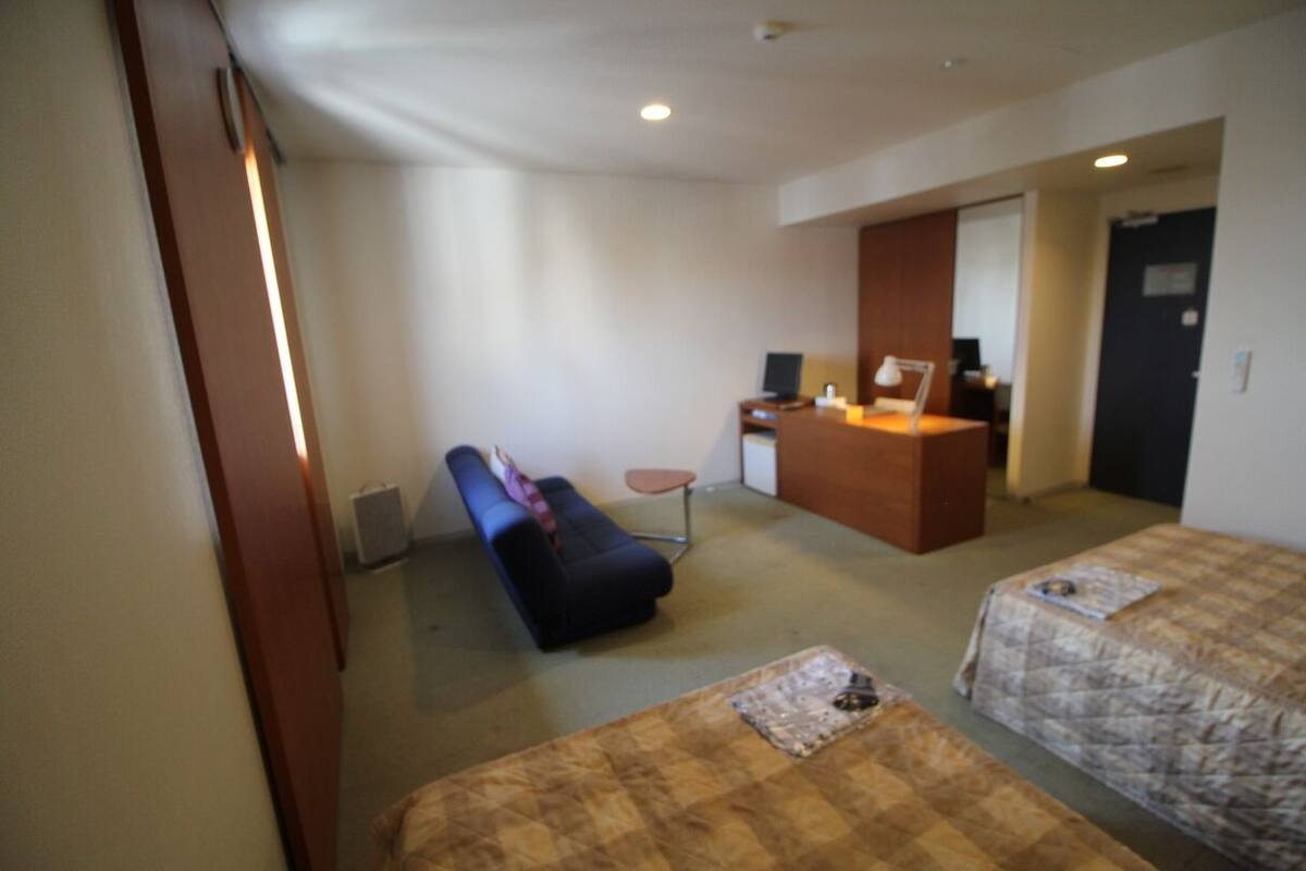 Ein Hotelzimmer mit Bett, Schreibtisch, Stuhl und Sofa.