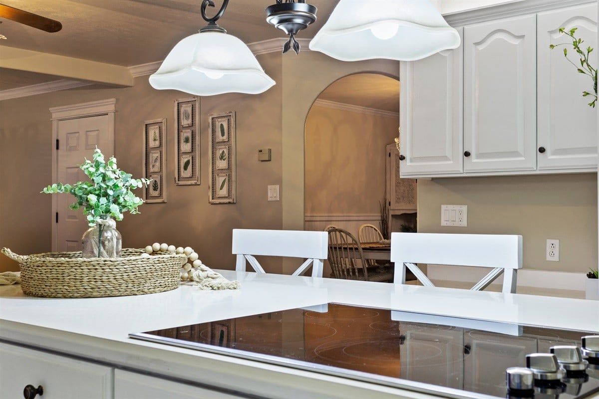 A kitchen with a central island, white cabinetry, and pendant lighting.