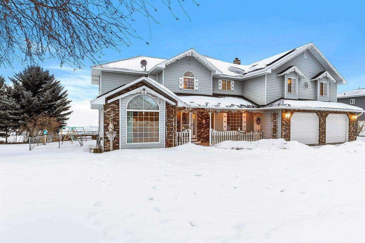 A large two-story house with a garage, a covered porch, and a snow-covered driveway.