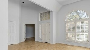 A hallway with white walls, wooden flooring, and a large arched window with blinds. - Stunning views of 17th hole at Austin Country Club.  (Austin)