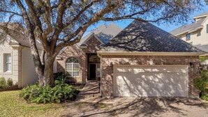 A residential house with a brick garage, a large tree in the front yard, and a clear sky. - Stunning views of 17th hole at Austin Country Club.  (Austin)