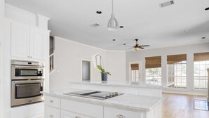 A spacious kitchen with white cabinetry, a large island, and a ceiling fan. - Stunning views of 17th hole at Austin Country Club.  (Austin)