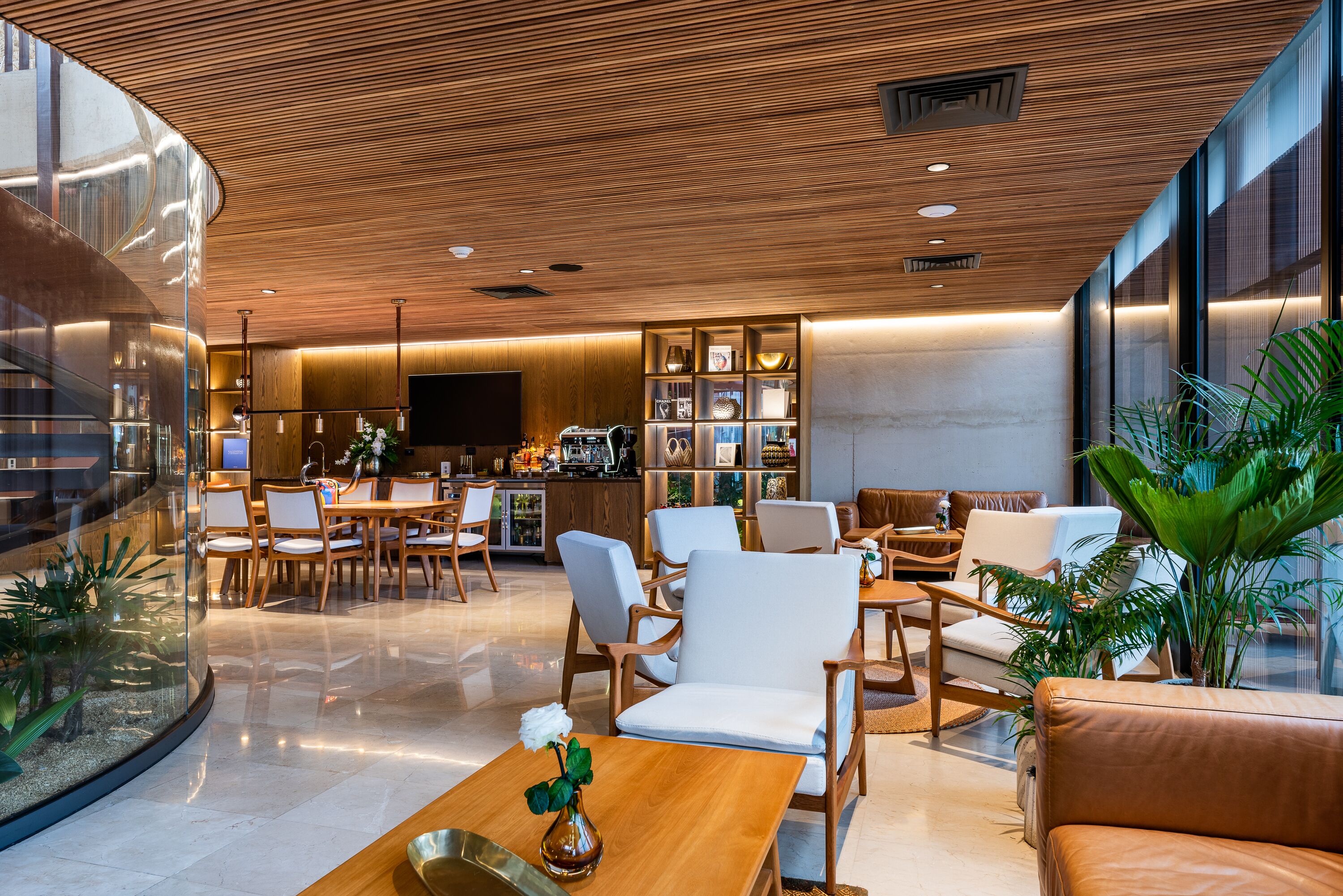 A modern hotel lobby with wooden ceiling, a central dining area, and a bar.