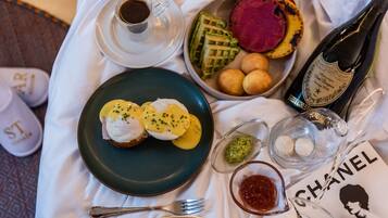A table with breakfast items including eggs Benedict, waffles, and a bottle of champagne.