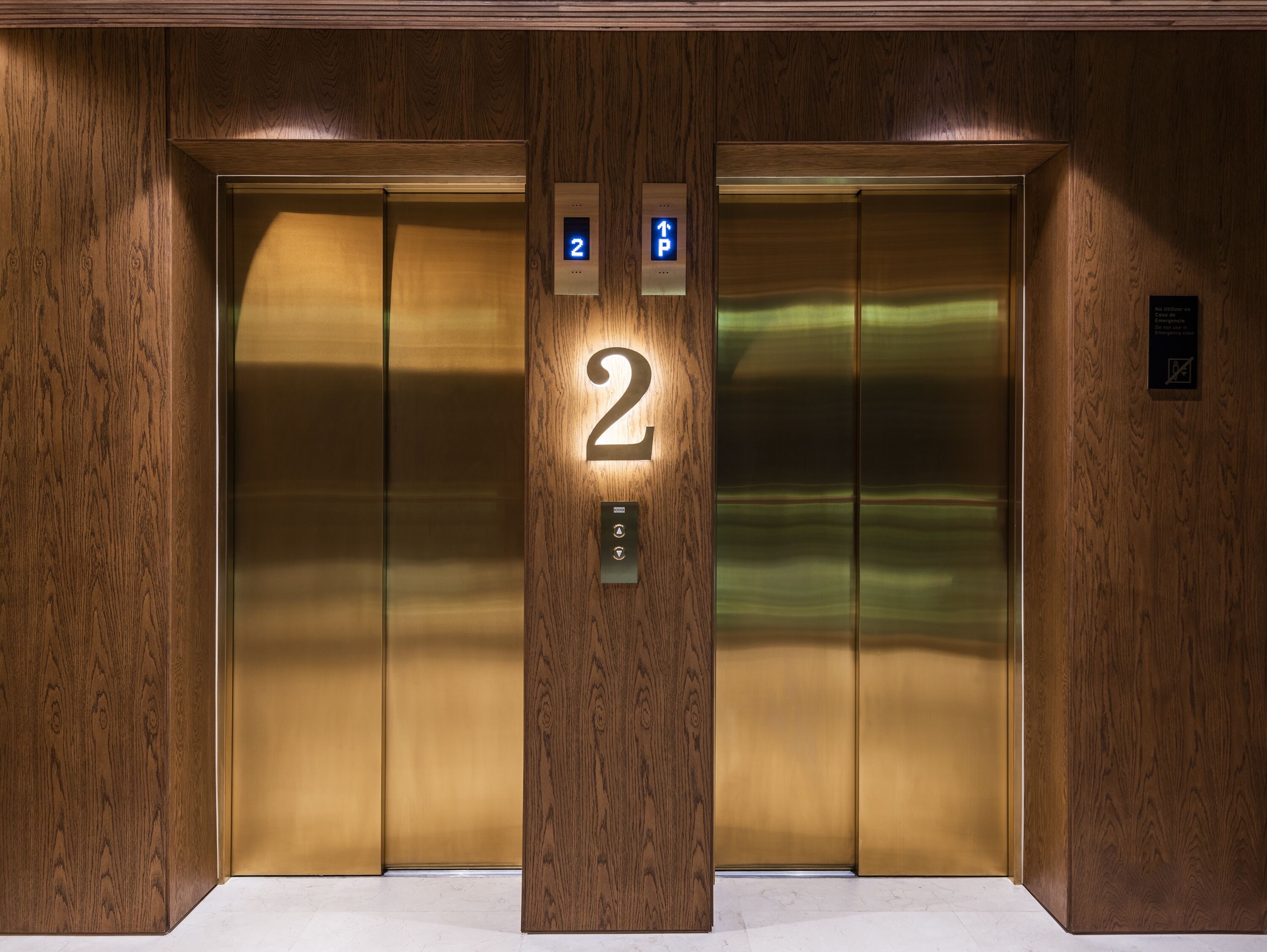 An elevator with a wooden panel wall, a number '2' sign, and a digital display indicating the floor.