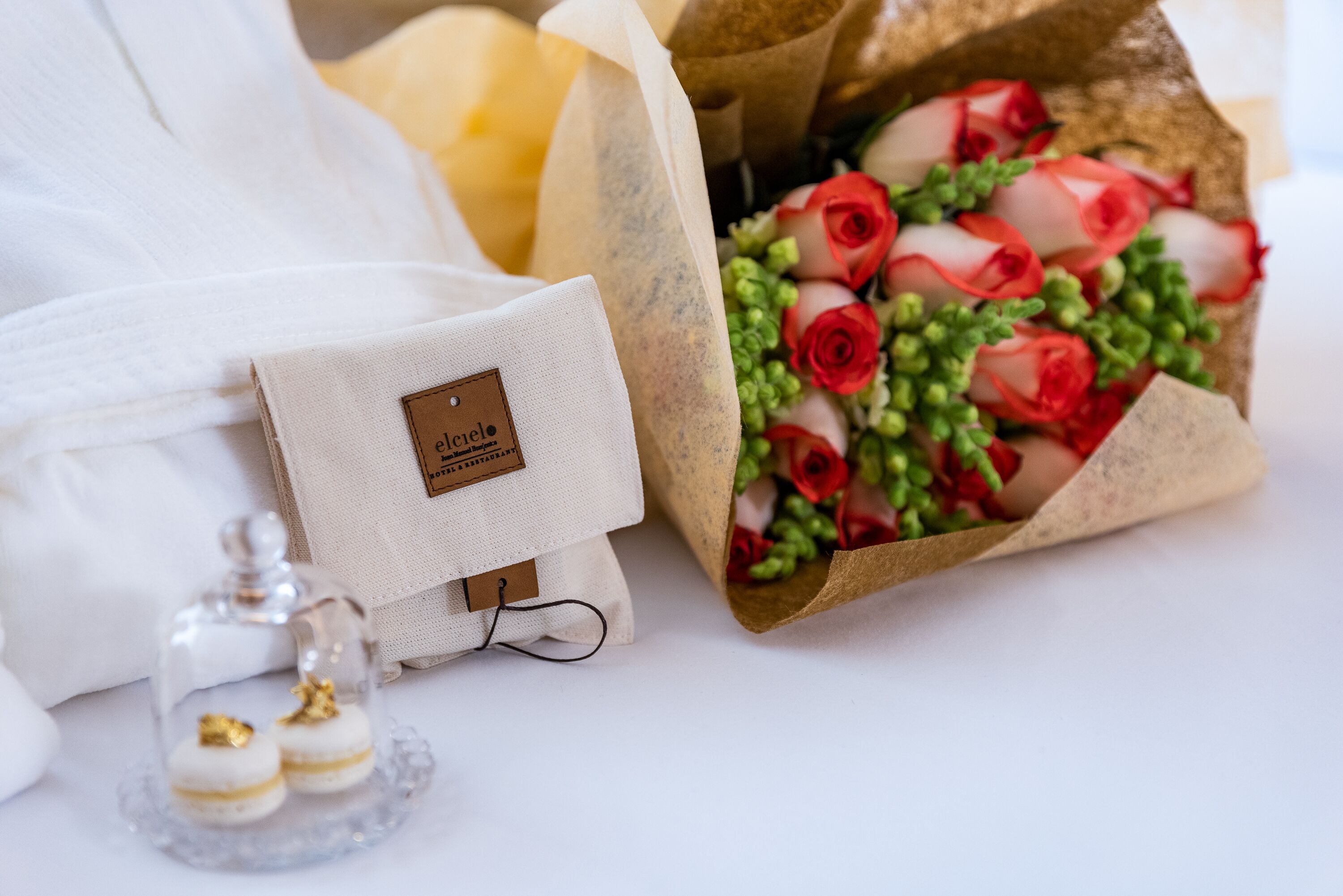 A white garment, a small white box with a label, and a bouquet of red roses wrapped in brown paper.
