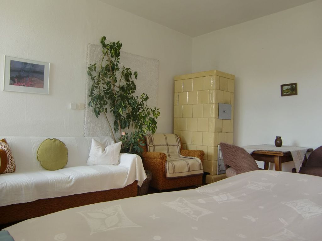 Habitación de hotel con dos camas, un sofá, una silla, una mesita y una planta en maceta.