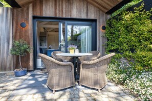 Eine Terrasse mit Korbstühlen, einem runden Tisch und einem Blumentopf.