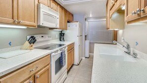 A kitchen with wooden cabinets, a microwave, a refrigerator, a sink, and a stove.