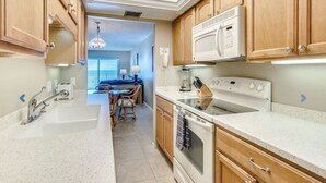A kitchen with wooden cabinets, a white countertop, a microwave, a stove, and a sink.