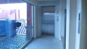 A narrow hallway with a tiled floor leading to an elevator. - Hotel Son Mar Monterrey Centro (Monterrey)