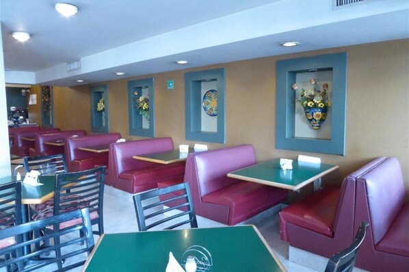 A restaurant interior with booths and tables, some with floral centerpieces. - Hotel Son Mar Monterrey Centro (Monterrey)