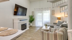 Ein modernes Wohnzimmer mit Kamin, einem an der Wand befestigten Flachbildfernseher, einer Couch und einem gestreiften Sessel.