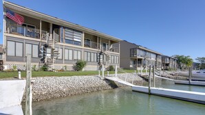 Ein mehrgeschossiges Hotel mit Balkonen, einer Flagge und einem Steg, der sich über das Wasser erstreckt.