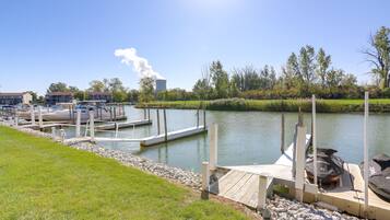 A marina with docked boats, a grassy area, and a cooling tower in the background.