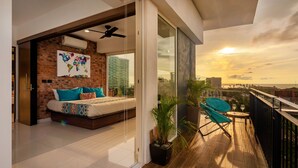 A modern bedroom with a brick wall, a large bed, and a city view. - Stylish Golden Beach View Apartmen (Puerto Vallarta)