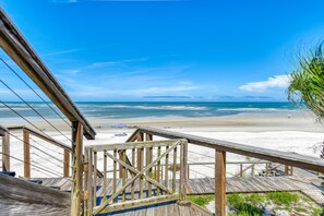 A wooden staircase leading to a beach with a clear view of the ocean.