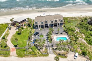 A beachfront hotel with multiple buildings, a swimming pool, and a parking area.