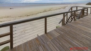 Una terrassa de fusta amb barana que dona a una platja.