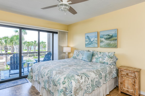 A bedroom with a bed, a view of the outdoors, a ceiling fan, and artwork on the wall. - Spectacular Oceanfront Condo ~ Excellent Location! (Saint Augustine)