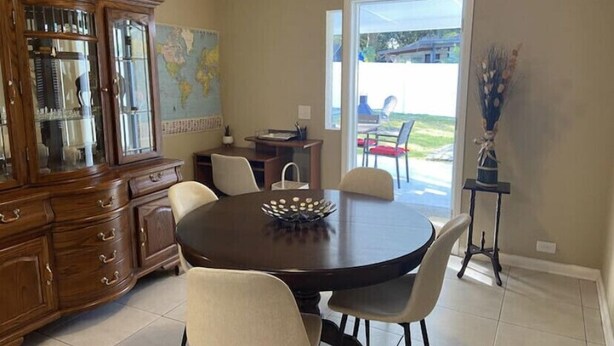Un coin repas comprenant une table ronde, quatre chaises, un buffet en bois avec des portes en verre et une carte accrochée au mur.