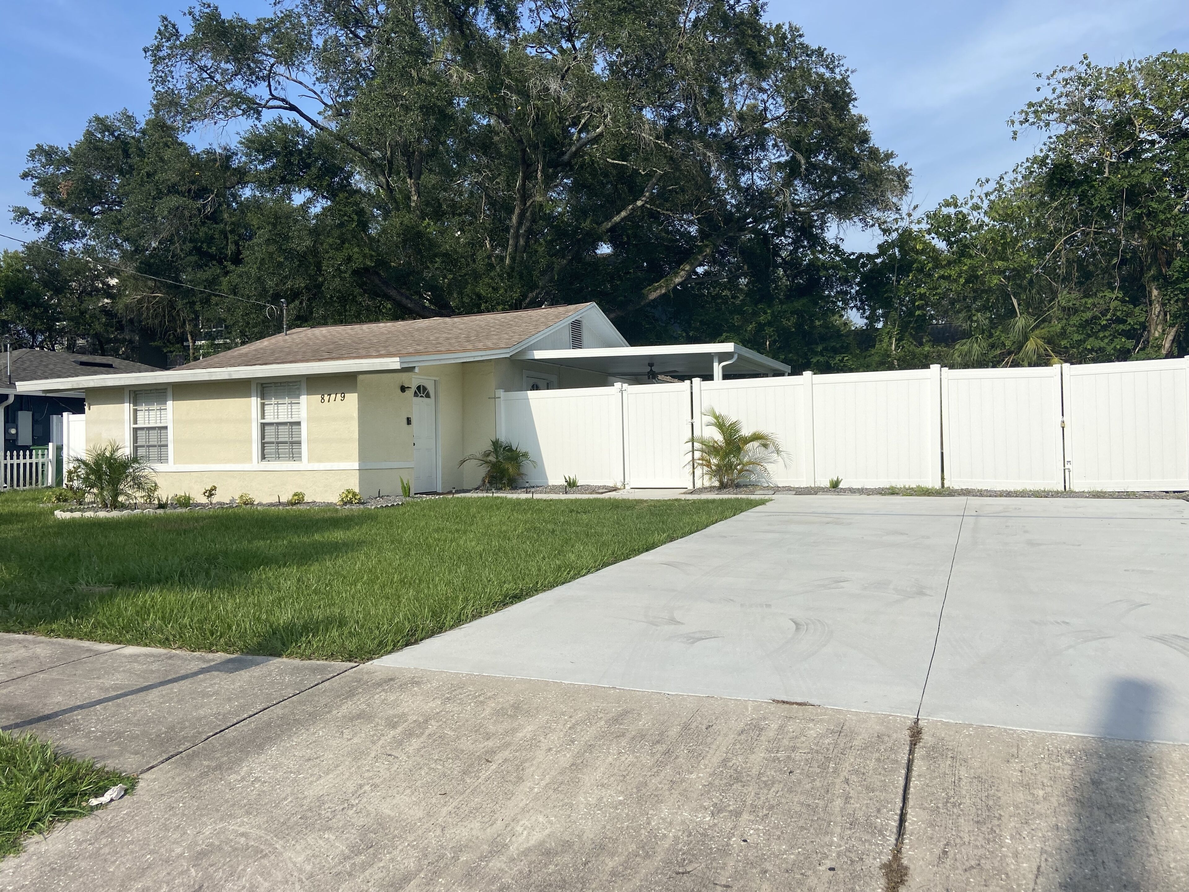A single-story house with a front yard, a white fence, and a driveway.