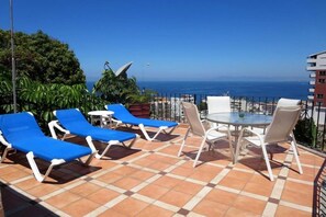 A terrace with blue lounge chairs, a round table, and a view of the sea. - Casa Anita y Corona del Mar Boutique (Puerto Vallarta)