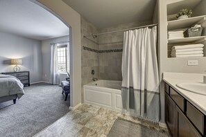 Een moderne badkamer met een bad, douchegordijn en een wastafelmeubel met wastafel.