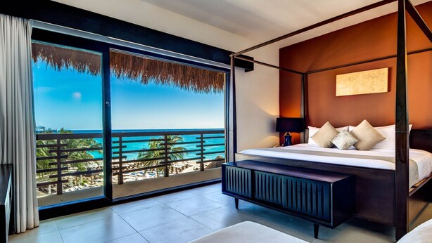 Ein modernes Schlafzimmer mit großem Balkon, einem Bett mit weißer Bettwäsche und Meerblick.