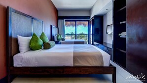 Ein modernes Schlafzimmer mit einem großen Bett, grünen Kissen und Blick auf Palmen.