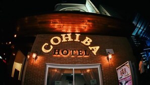 El exterior del Hotel Cohiba con letreros iluminados y fachada de ladrillo.
