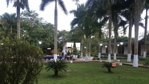 Pátio com palmeiras, piscina e área de estar externa.