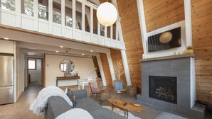 Amplia sala de estar con chimenea, un sofá y un comedor con mesa y sillas.
