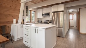 Una cocina moderna con armarios blancos, electrodomésticos de acero inoxidable y piso de madera.