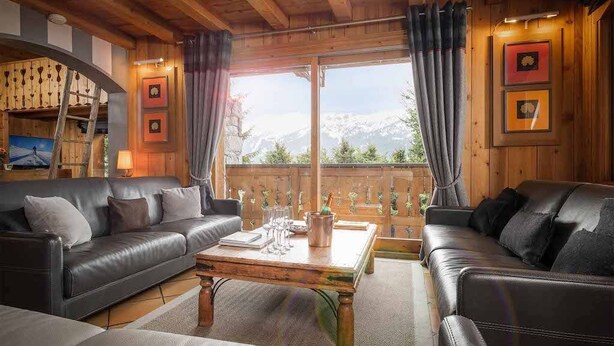 Una sala de estar acogedora con dos sofás de cuero, una mesa de centro de madera y un ventanal con cortinas.